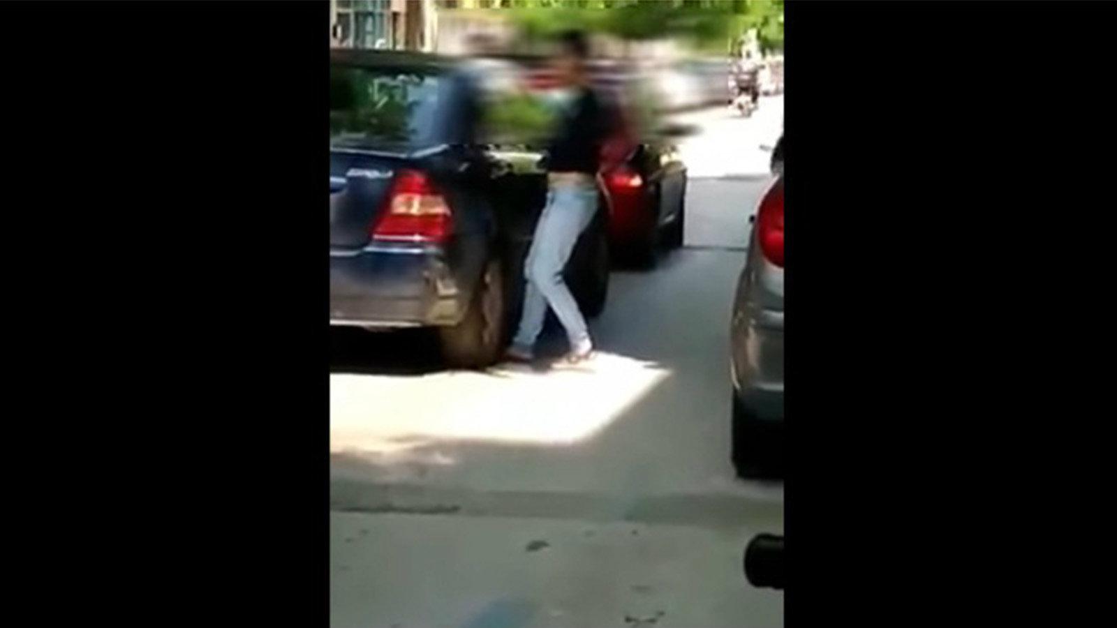 Η νεαρή βάζει το πόδι της μπροστά από την ρόδα ενός αυτοκινήτου που είναι σταματημένο σε φανάρι.