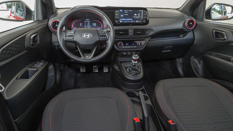 Οι κόκκινες ραφές, τα λογότυπα και τα αλουμινένια στοιχεία δίνουν μια αγωνιστική αίσθηση στην καμπίνα 