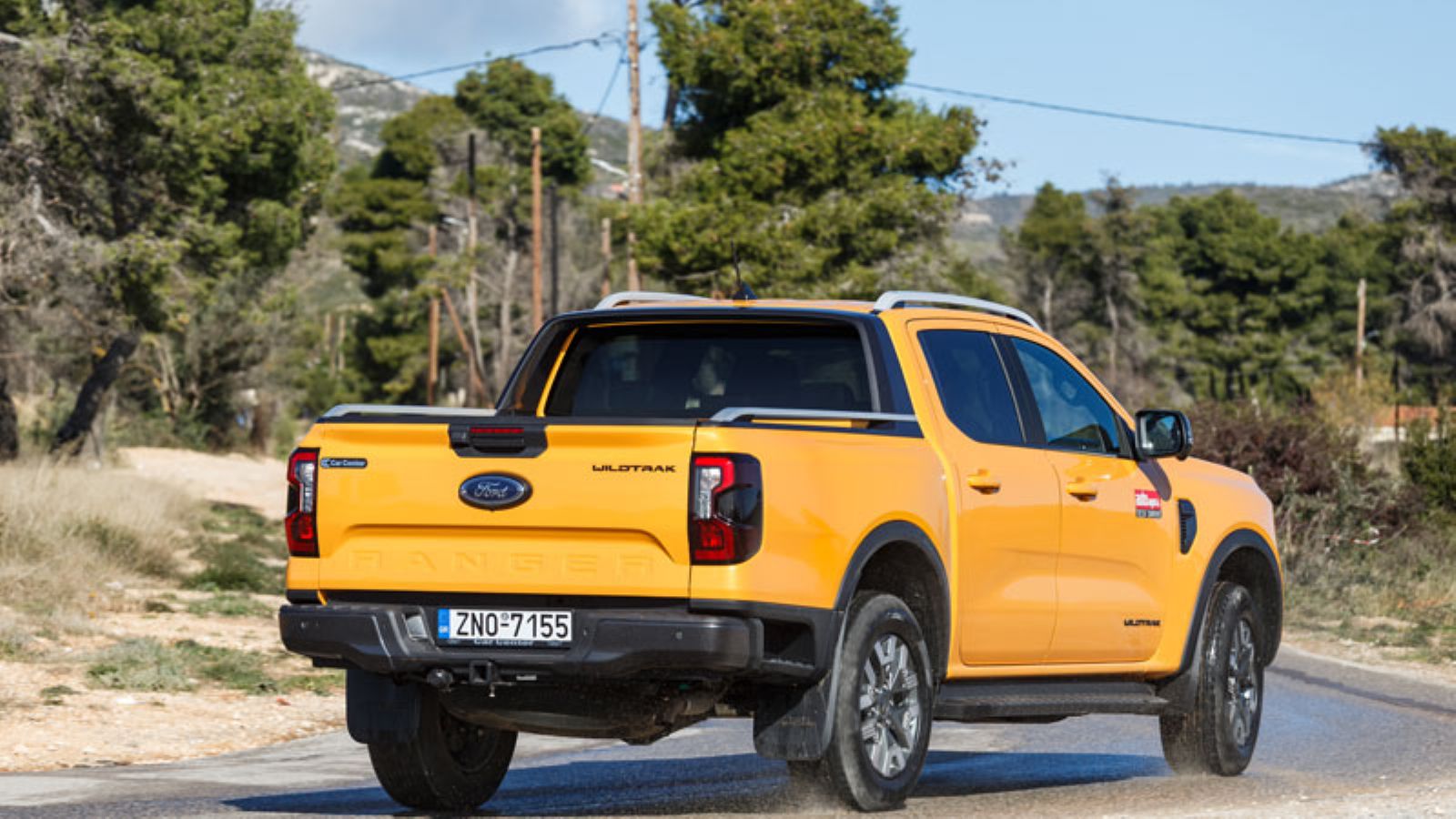 Το Ford Ranger PHEV από πίσω σε στροφή σε άσφαλτο, δεξιά πλευρά