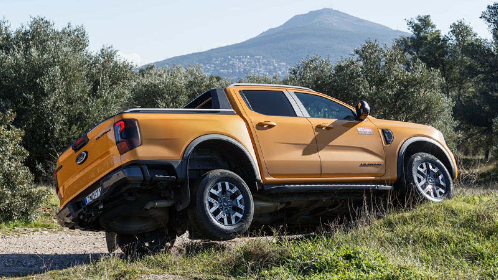 Το Ford Ranger PHEV σκαρφαλωμένο σε ανάχωμα, από την πίσω πλευρά, με τον πίσω δεξί τροχό να κρέμεται